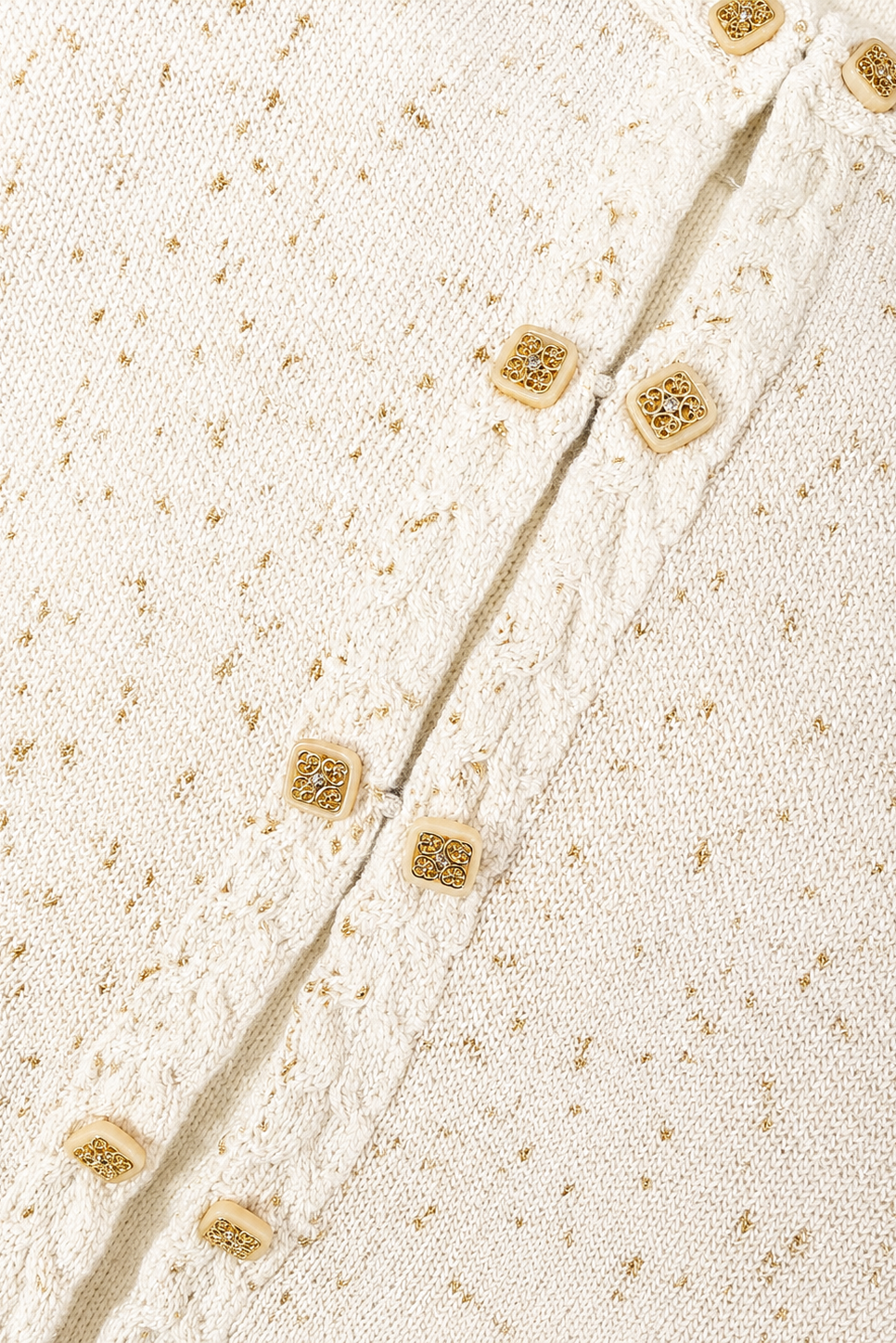Close-up of a textured fabric with gold buttons on a beige background