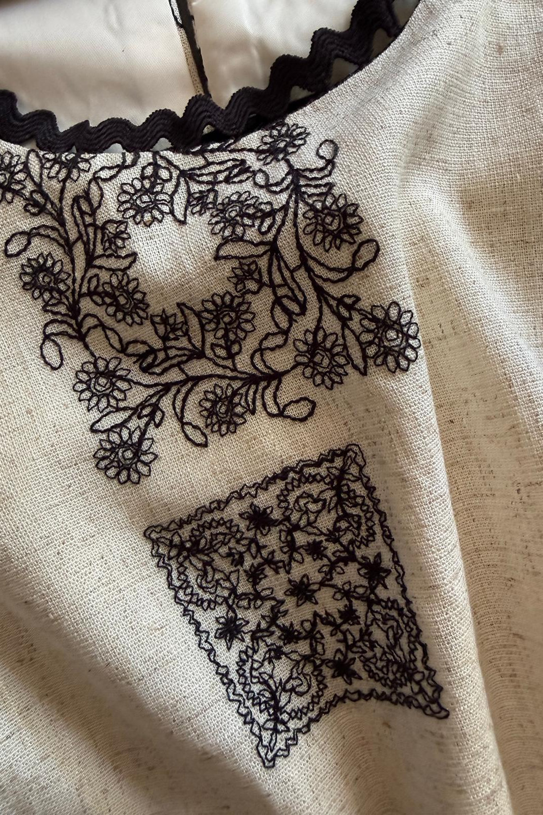 Women's ivory embroidered sleeveless crop top with black contrast trim and elegant embroidered detailing.