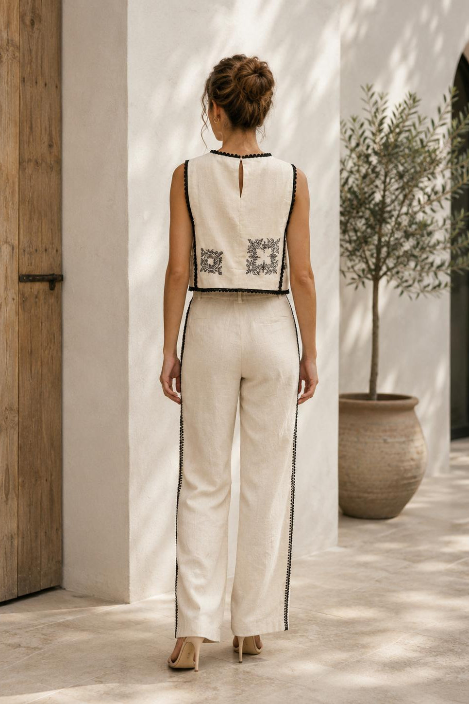 Women's ivory embroidered sleeveless crop top with black contrast trim and elegant embroidered detailing.