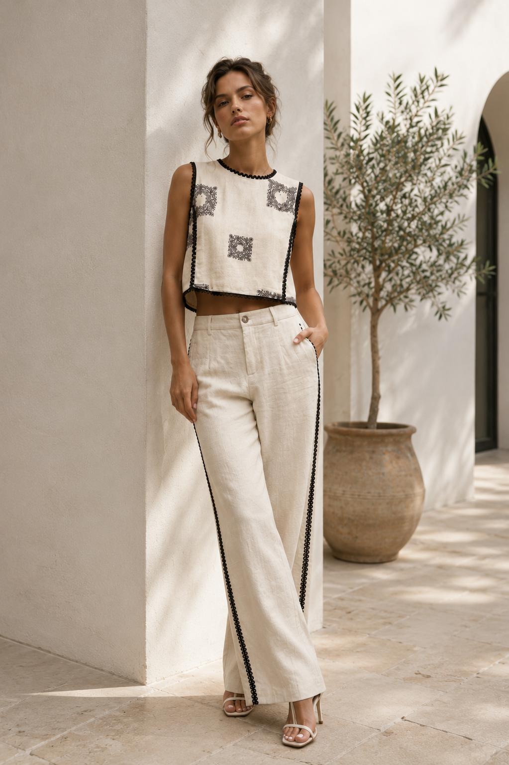 Women's ivory embroidered sleeveless crop top with black contrast trim and elegant embroidered detailing.
